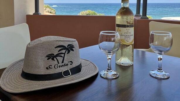 A balcony with a table set for two, featuring a bottle of white wine and two wine glasses. - Iolkos Hotel Apartments (Chania)