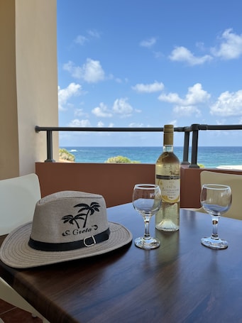 A balcony with a table set for two, featuring a bottle of white wine and two wine glasses.