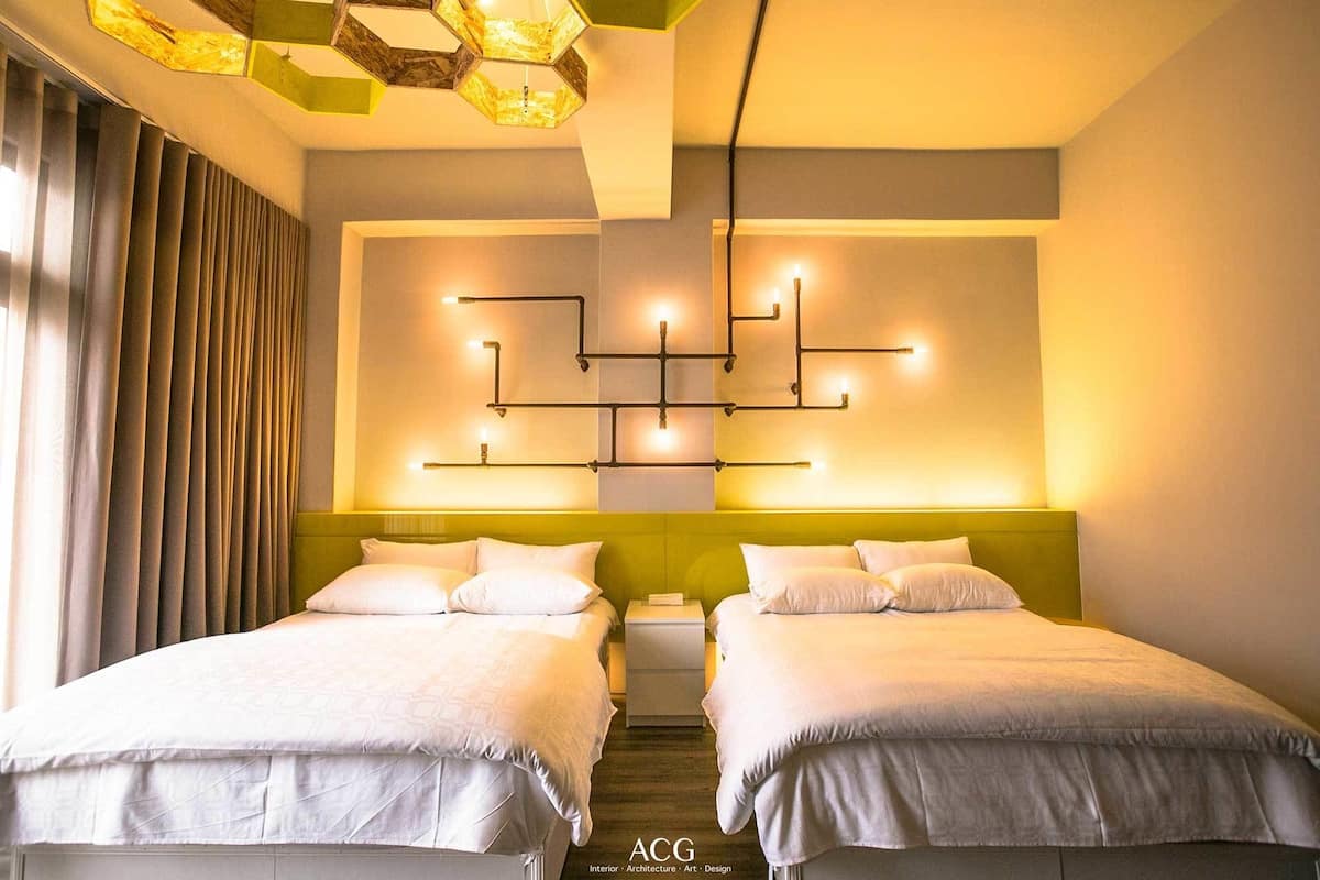 A hotel room with two beds, a modern light fixture, and a staircase.
