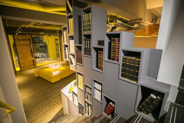 Una biblioteca moderna con estanterías y un sofá amarillo.