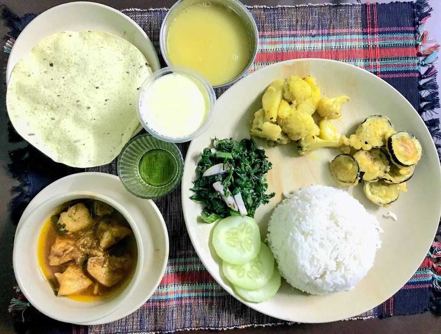A plate with white rice, sliced cucumbers, a green salad, cauliflower, and zucchini slices.