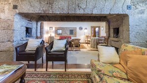 A stone-walled living room with a fireplace, leather chairs, a sofa, and a rug. - Pazo de Sedor (Arzua)