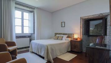 A bedroom with a bed, a nightstand, a desk, and a chair.