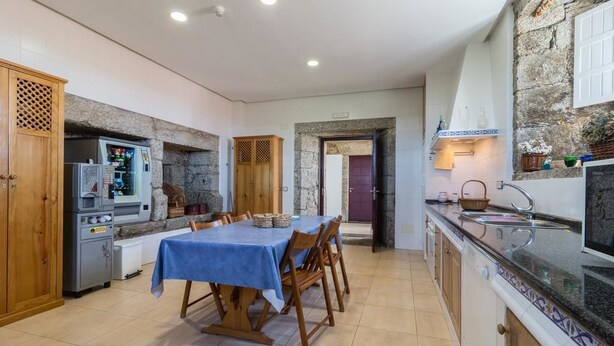 Una cocina con una mesa de comedor, armarios de madera, un refrigerador y una máquina expendedora.