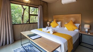 Un dormitorio con cama, mesitas de noche, un escritorio, una ventana con cortinas y un equipo de aire acondicionado.