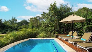 Una piscina con sillas de descanso y una sombrilla.