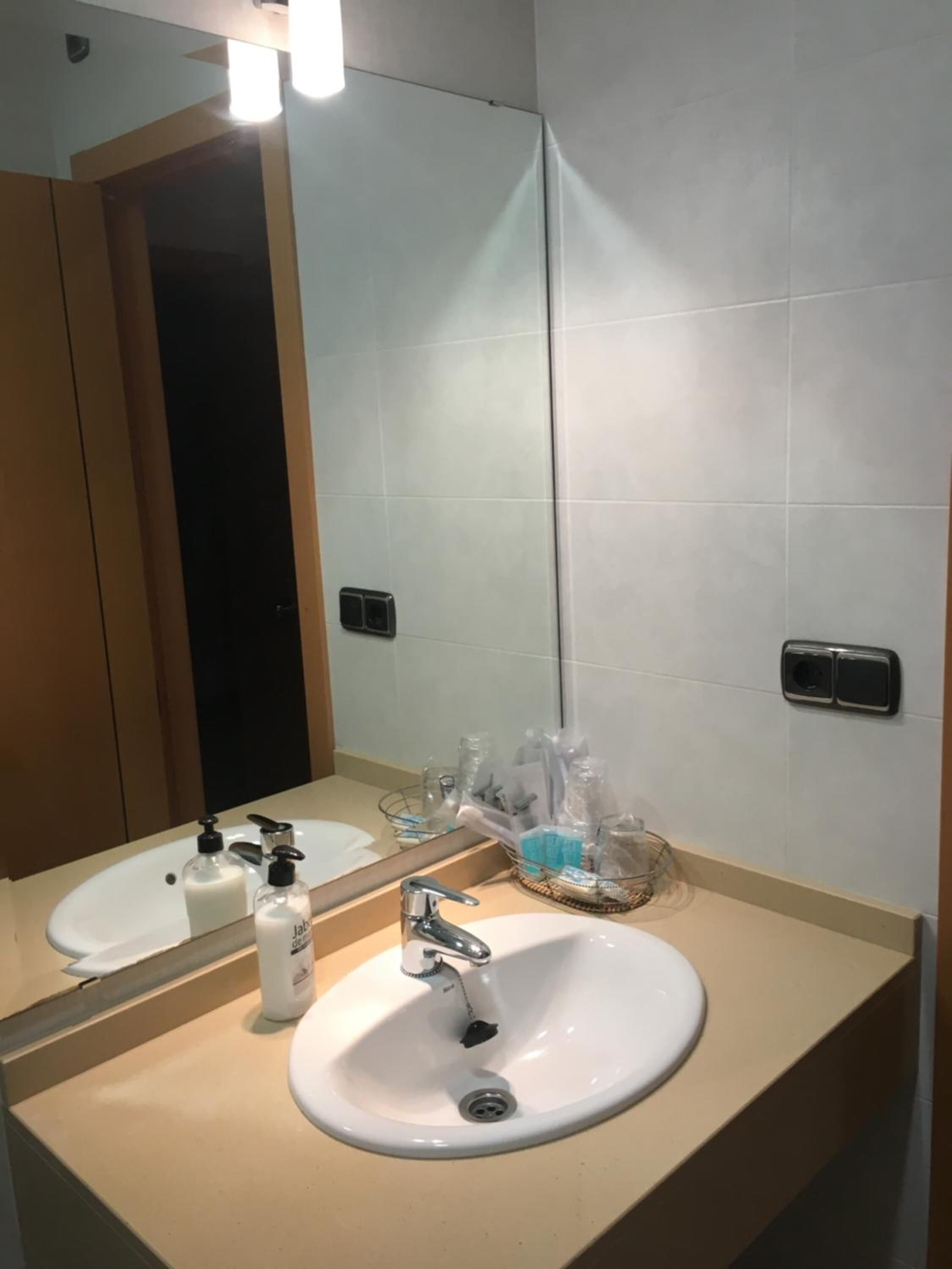 A bathroom with a white sink, a mirror, and a towel rack.
