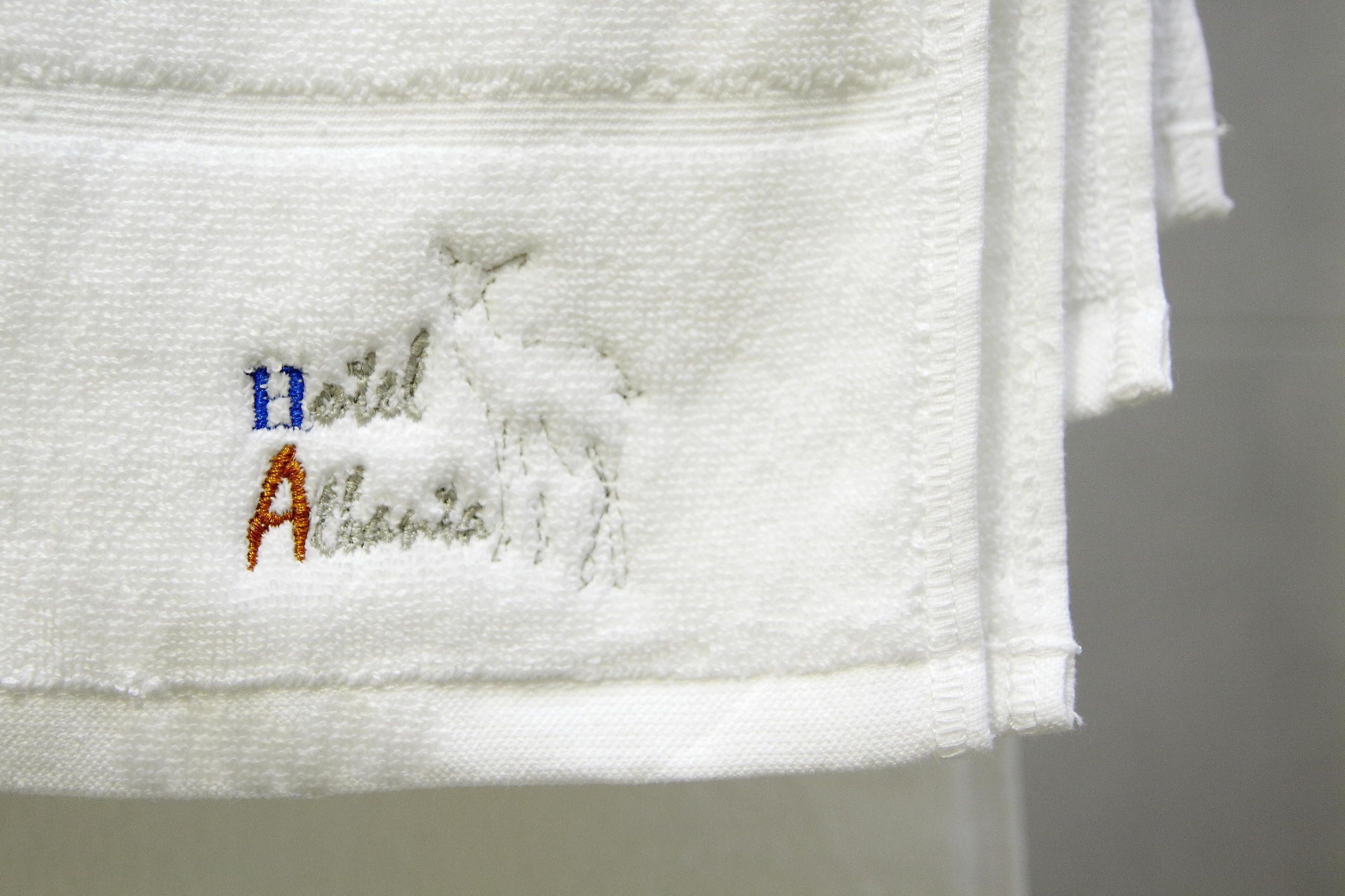 Une serviette blanche ornée d’un texte brodé et d’un logo.