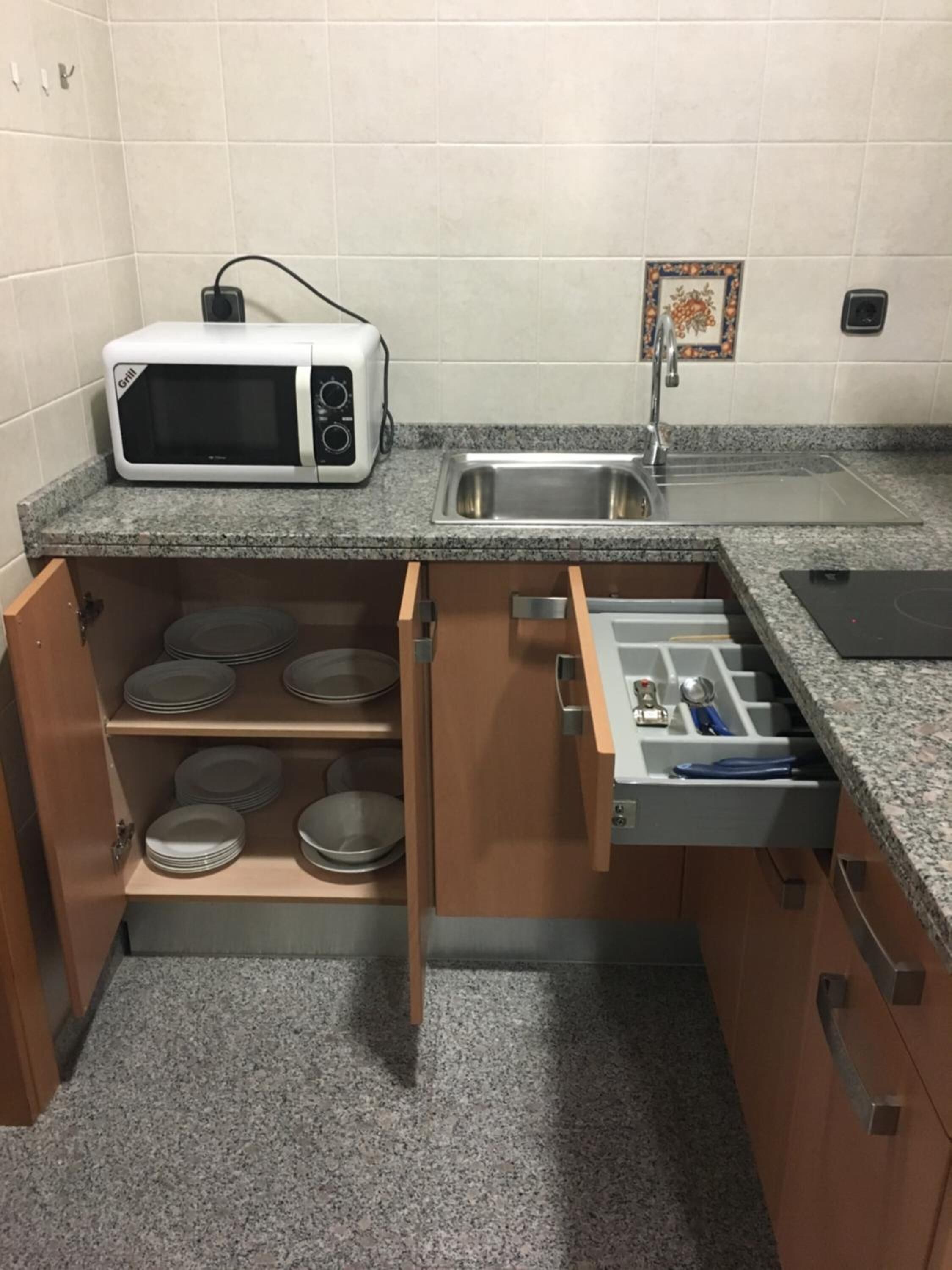 Une cuisine compacte équipée d’un four à micro-ondes, d’un évier et de tiroirs de rangement intégrés.