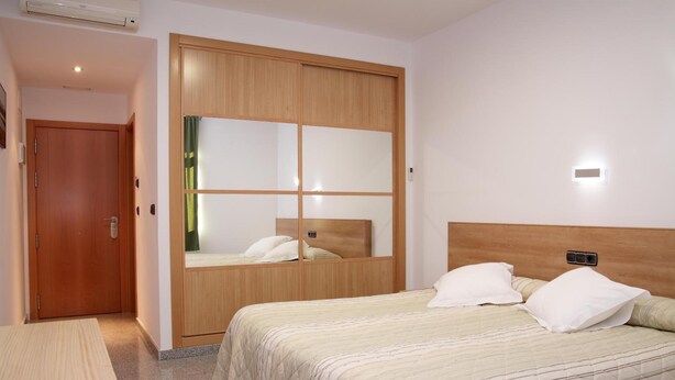 A bedroom with a bed, a wardrobe, and a mirror. - Hotel Albanta (La Lantejuela)