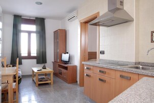 Una cocina compacta con armarios de madera, encimera de granito y horno integrado.