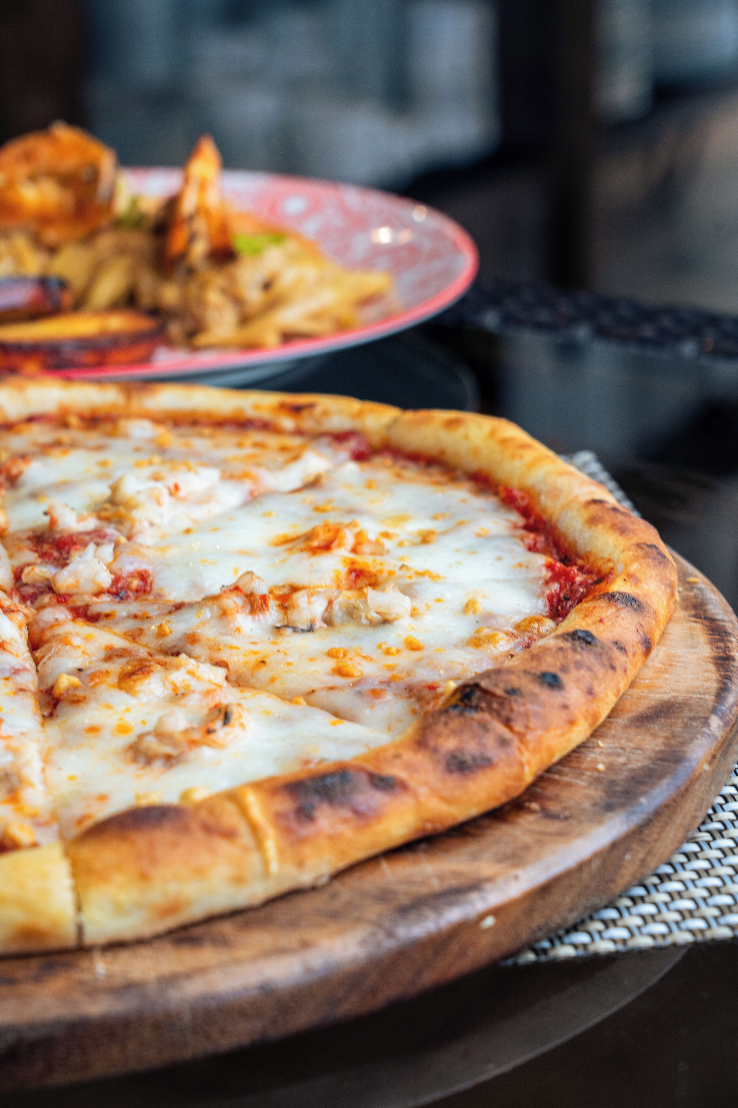 A pizza on a wooden board with a blurred background.