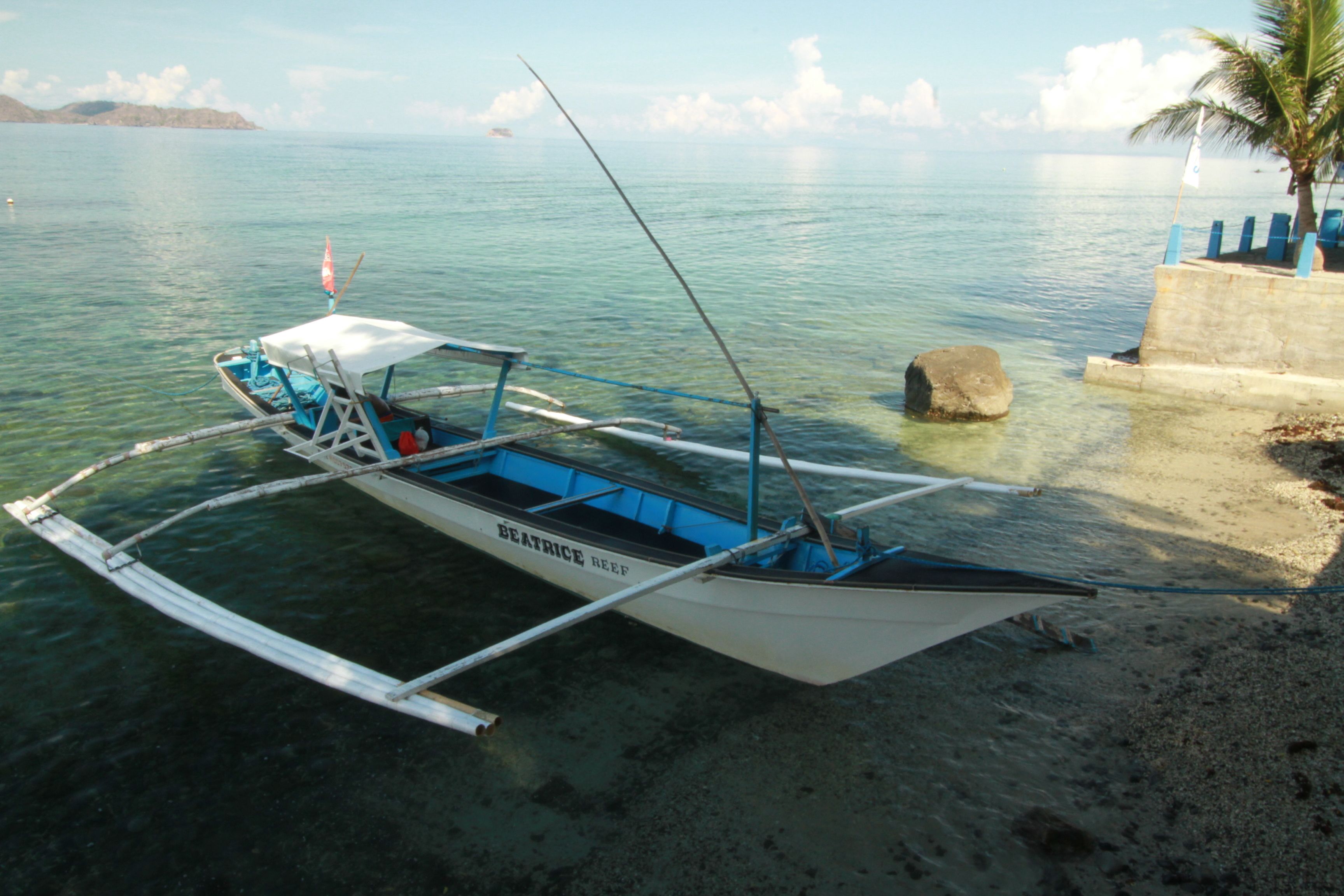 A boat named 'BEATRICE REEF' docked at a beach with clear water and a sandy shore.