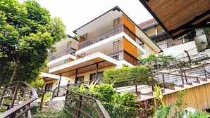A multi-story hotel with balconies, a staircase, and lush greenery.