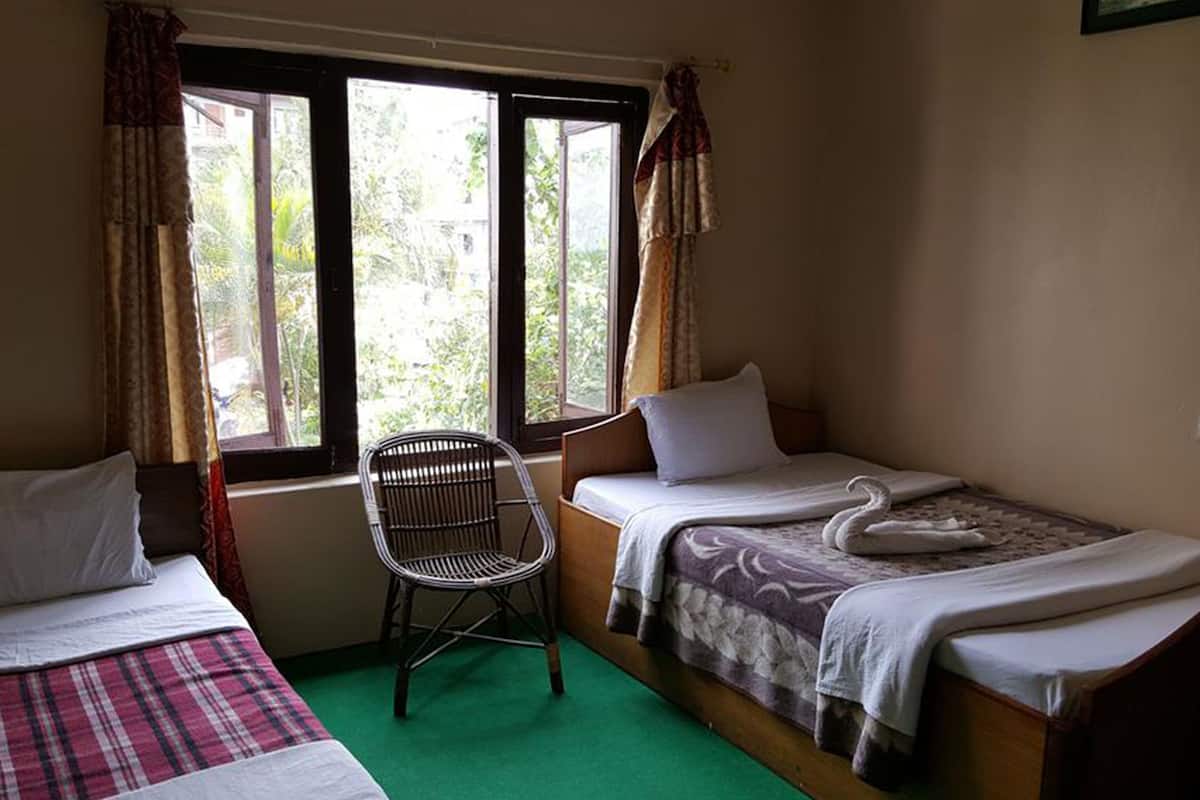 Une chambre avec deux lits simples, une chaise et une fenêtre avec des rideaux.