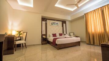 Una habitación de hotel con cama, escritorio, silla y ventilador de techo.