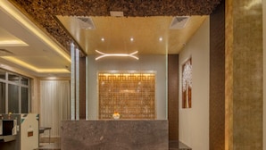 Un área de recepción con mostrador de mármol, un muro decorativo e iluminación empotrada en el techo.