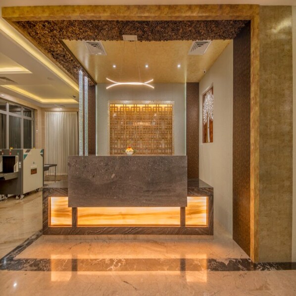 A reception area with a marble counter, a decorative wall, and a ceiling with recessed lighting.