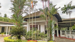 A building with a tiled roof, surrounded by lush greenery and palm trees. - Kitulgala Heritage Rest House (Kithulgala)