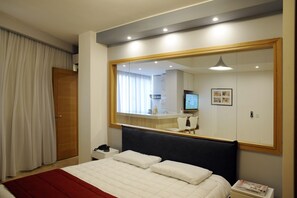 A hotel room with a large bed, a bedside table with a lamp, a mirror, and a view of the bathroom. - Grey Pearls Suites (Jounieh)