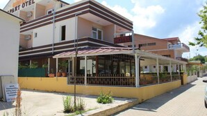 Een hotel met een overdekt terras, een bord met daarop 'Güneş Hotel' en een zichtbare ingang.