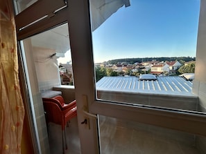 Un balcon donnant sur un quartier résidentiel, avec une chaise rouge et une table.