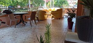 Een terras met buitenmeubilair, zoals stoelen en een bank, omringd door potplanten.