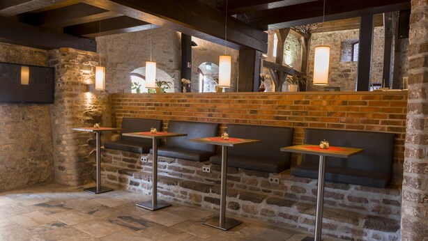 Un restaurante con paredes de ladrillo, pisos de piedra y asientos modernos.