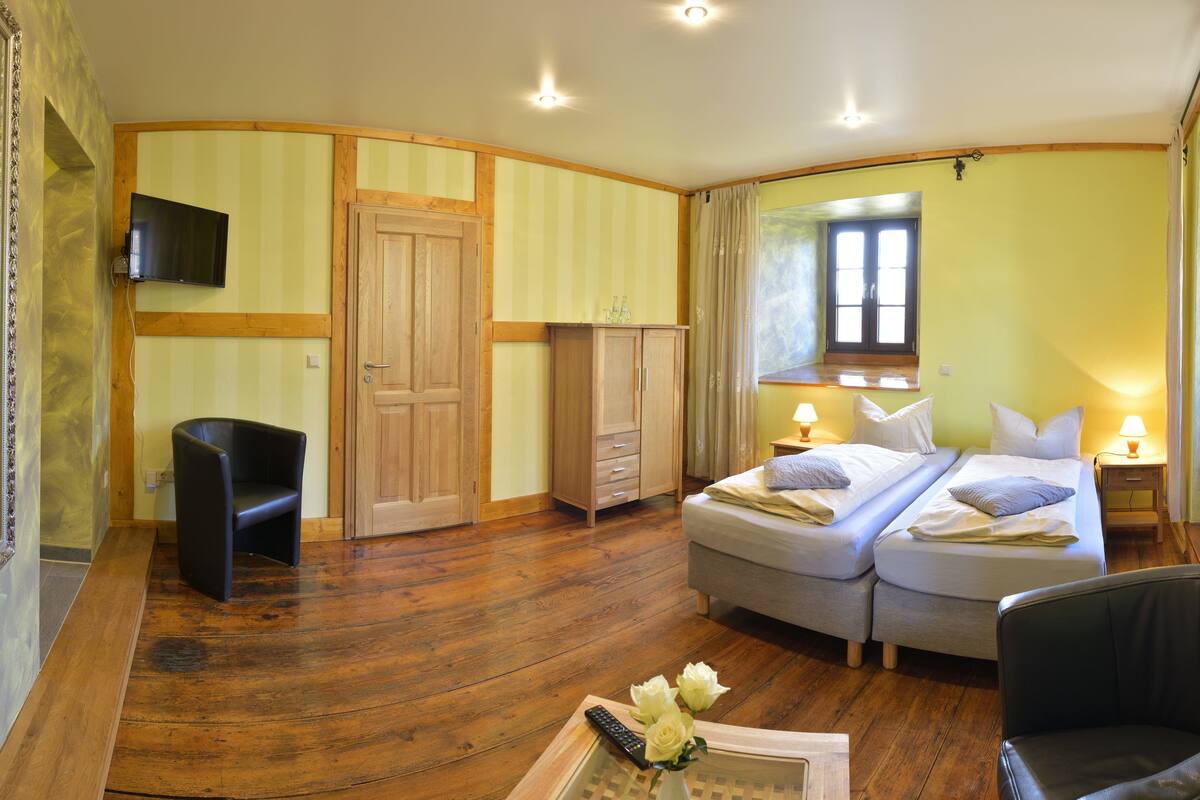Een slaapkamer met een tweepersoonsbed, een bureau, een stoel, een kledingkast en een televisie.