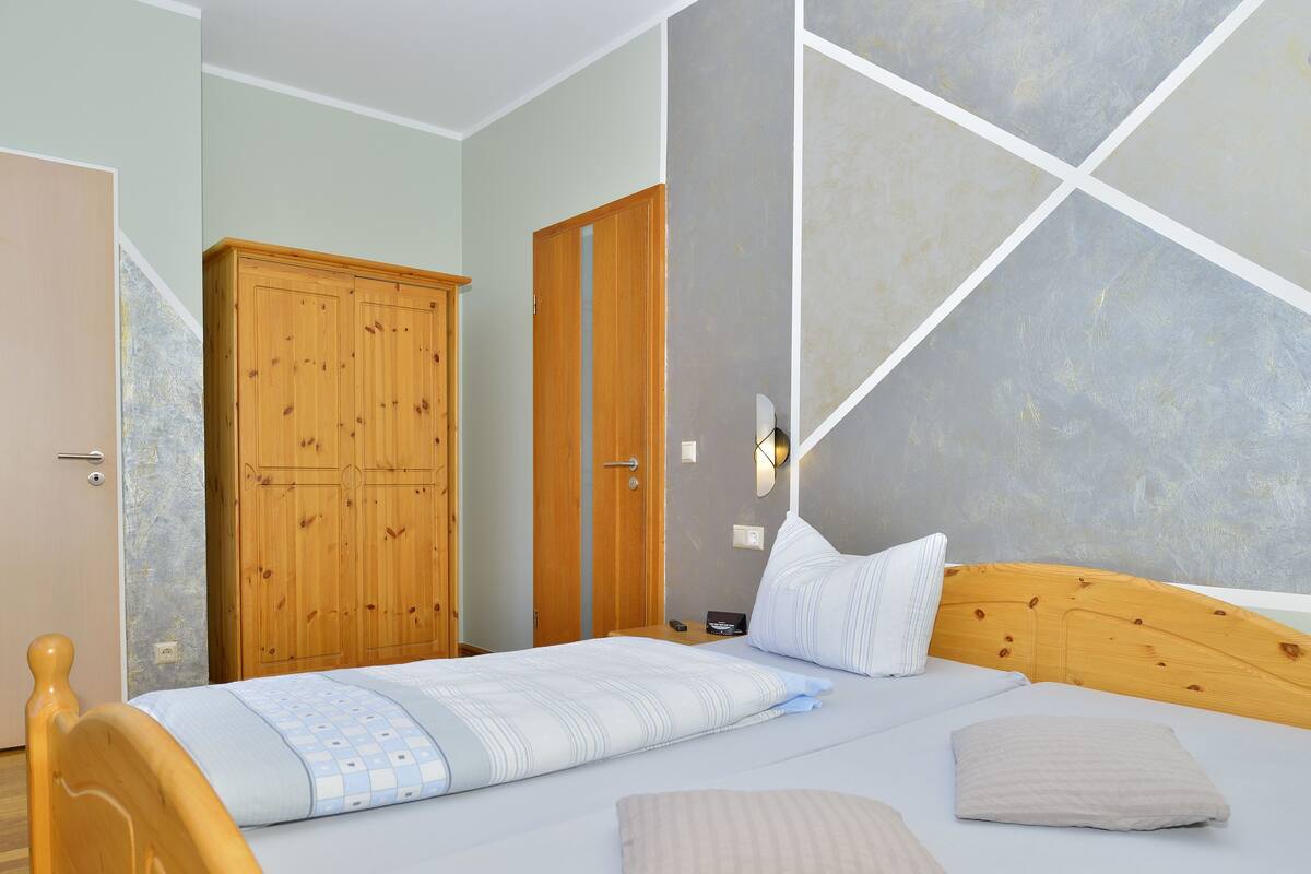 Een slaapkamer met een bed, een houten garderobe en een muur met geometrische patronen.