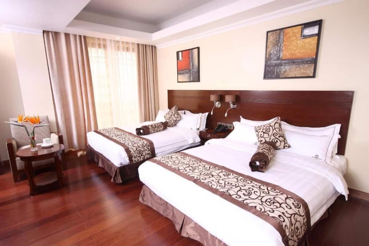 Een hotelkamer met twee bedden, een bureau en een stoel.
