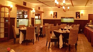 A restaurant with wooden flooring, wicker chairs, and tables set for dining.