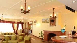 A cozy lounge area with wicker furniture, a fireplace, and a bar with a drink.