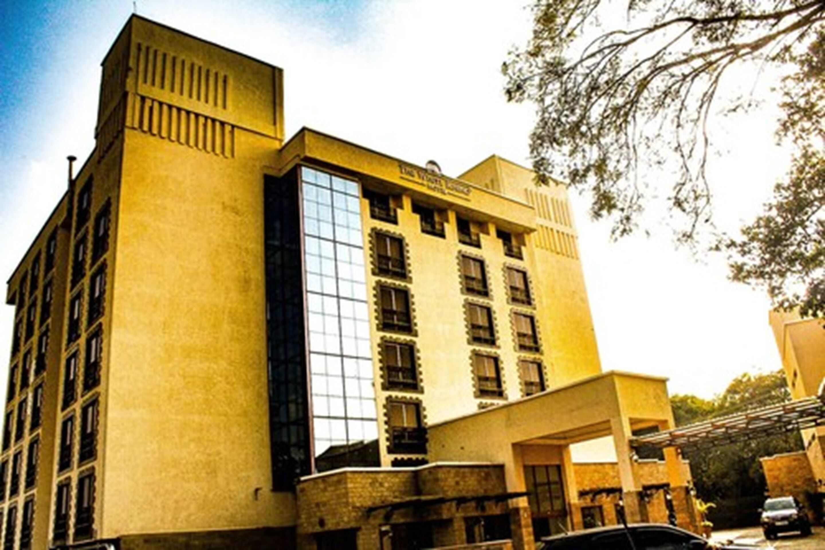 A multi-story hotel with a prominent glass facade, a flat roof, and a large entrance area.
