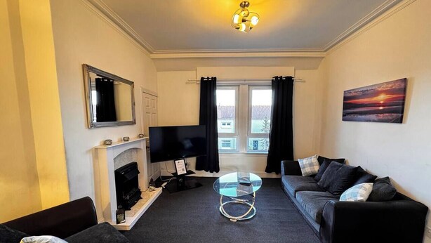 A living room with a fireplace, a TV, a sofa, and a coffee table. - The Wellesley Apartment (Methil)