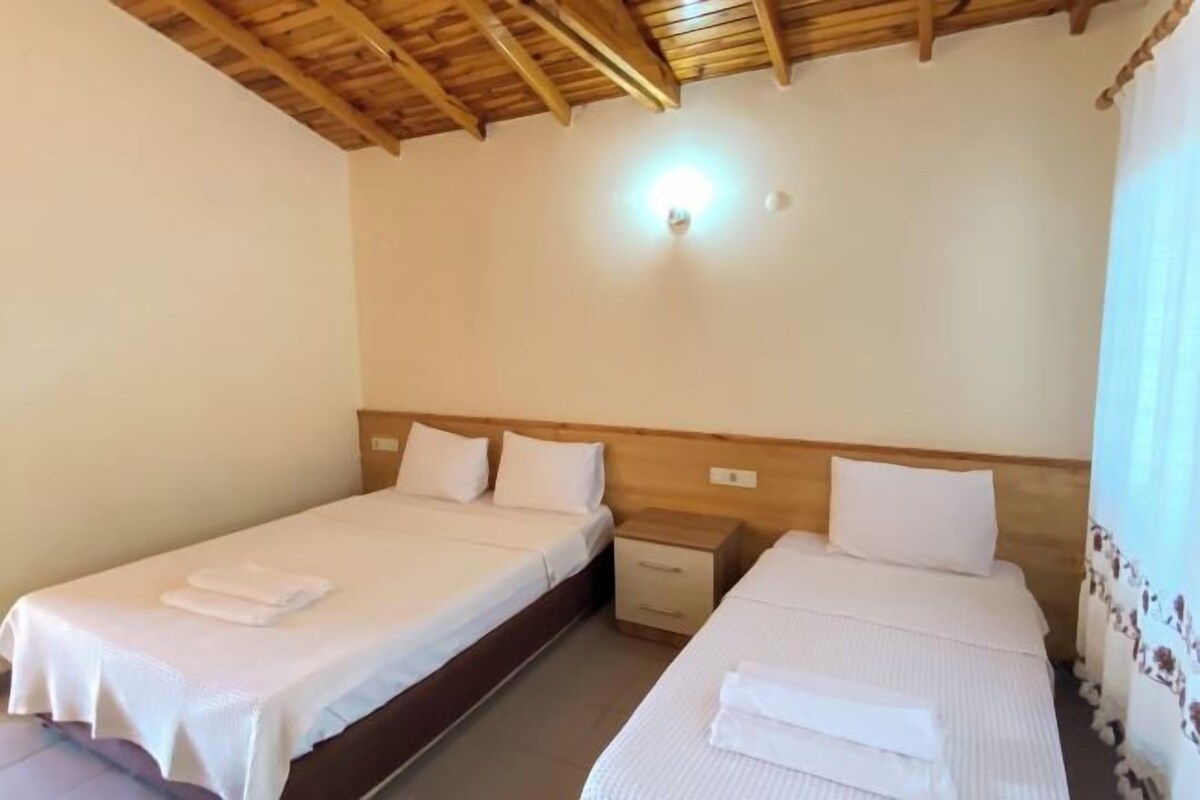 A room with two beds, wooden headboards, white bedding, and a ceiling light.