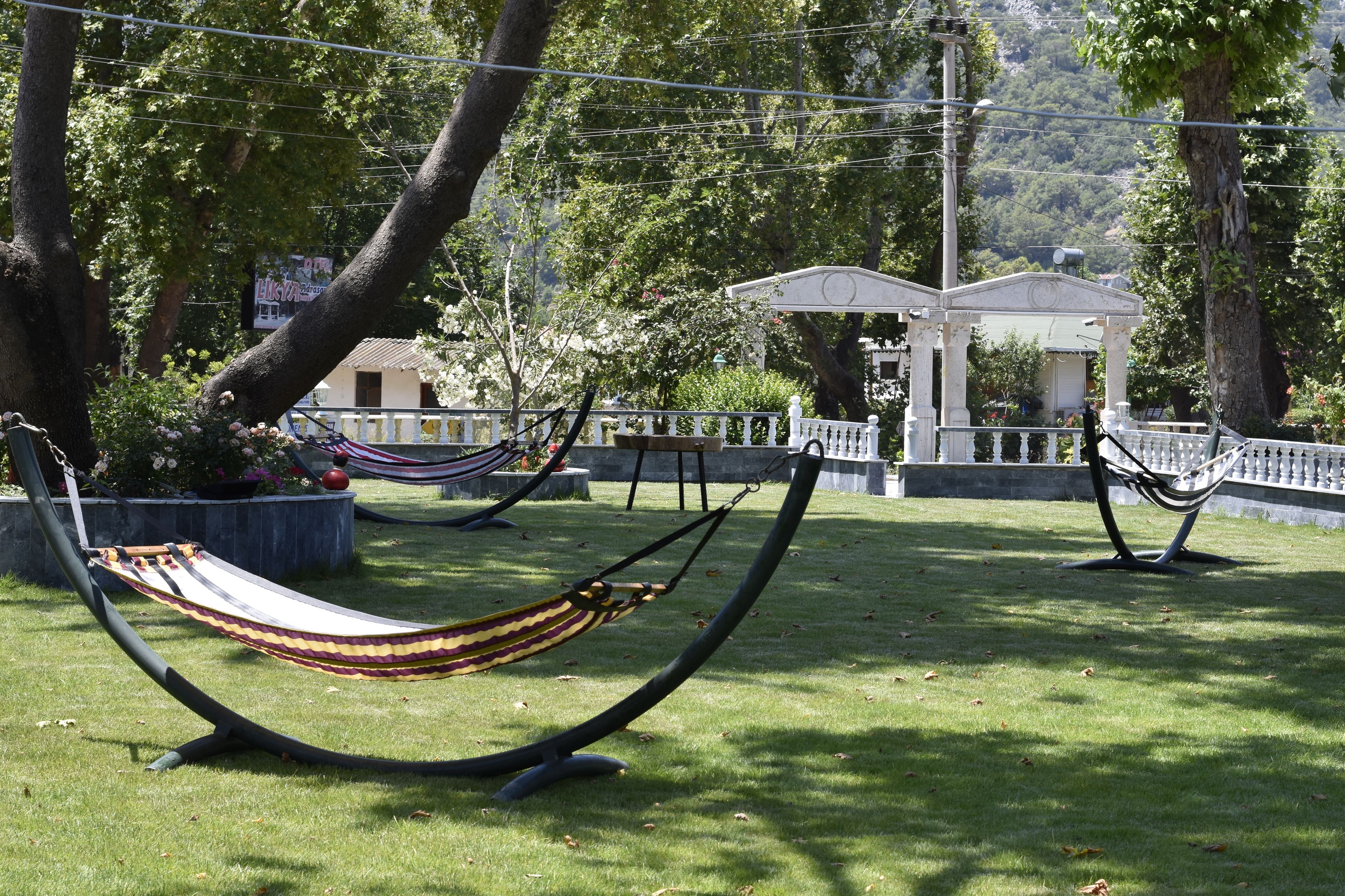 A grassy area with two hammocks and a white gazebo in the background.