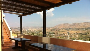 Un espace extérieur abrité, aménagé avec des sièges, et offrant une vue sur une vallée et des montagnes.
