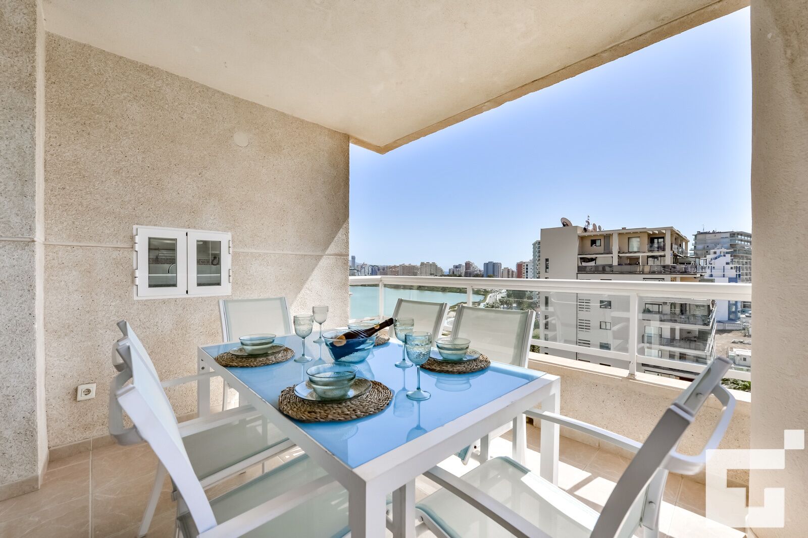 En balkon med et spisebord, med udsigt over bybilledet.