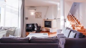 A modern living room with a sofa, TV, fireplace, and staircase. - Villa w/private pool in peaceful holiday complex (Albufeira)