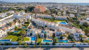 A coastal residential area with multiple white buildings, some with balconies, and several swimming pools. - Villa w/private pool in peaceful holiday complex (Albufeira)