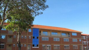 A multi-story building with a red-tiled roof, multiple windows, and a paved courtyard. - Ulrika Guest House (Entebbe)