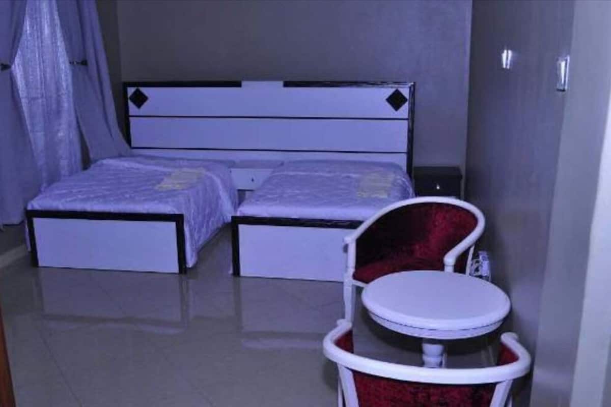 A small, compact room with a bed, a chair, and a small table.