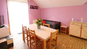 Una habitación acogedora con una mesa de comedor, sillas, un sofá y un armario.
