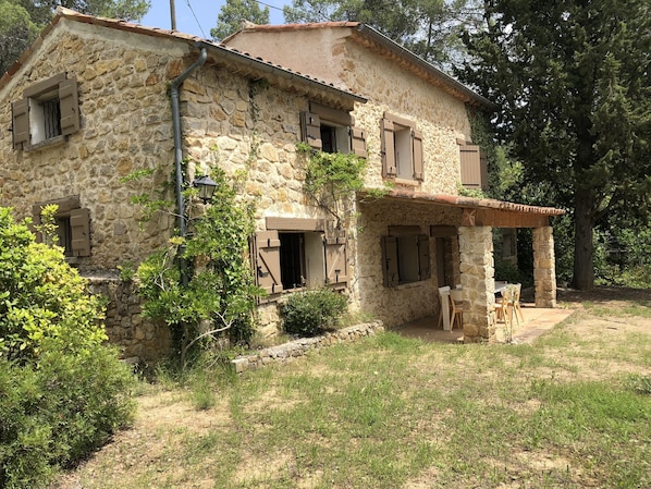A stone house with a covered porch and a table and chairs.