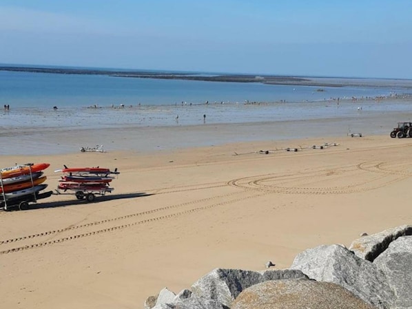 A beach with kayaks and a tractor.