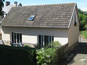 A small, single-story house with a tiled roof, a small window, and a door.