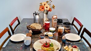 A dining table with various food items, a pitcher, a vase with flowers, and a carton of milk.