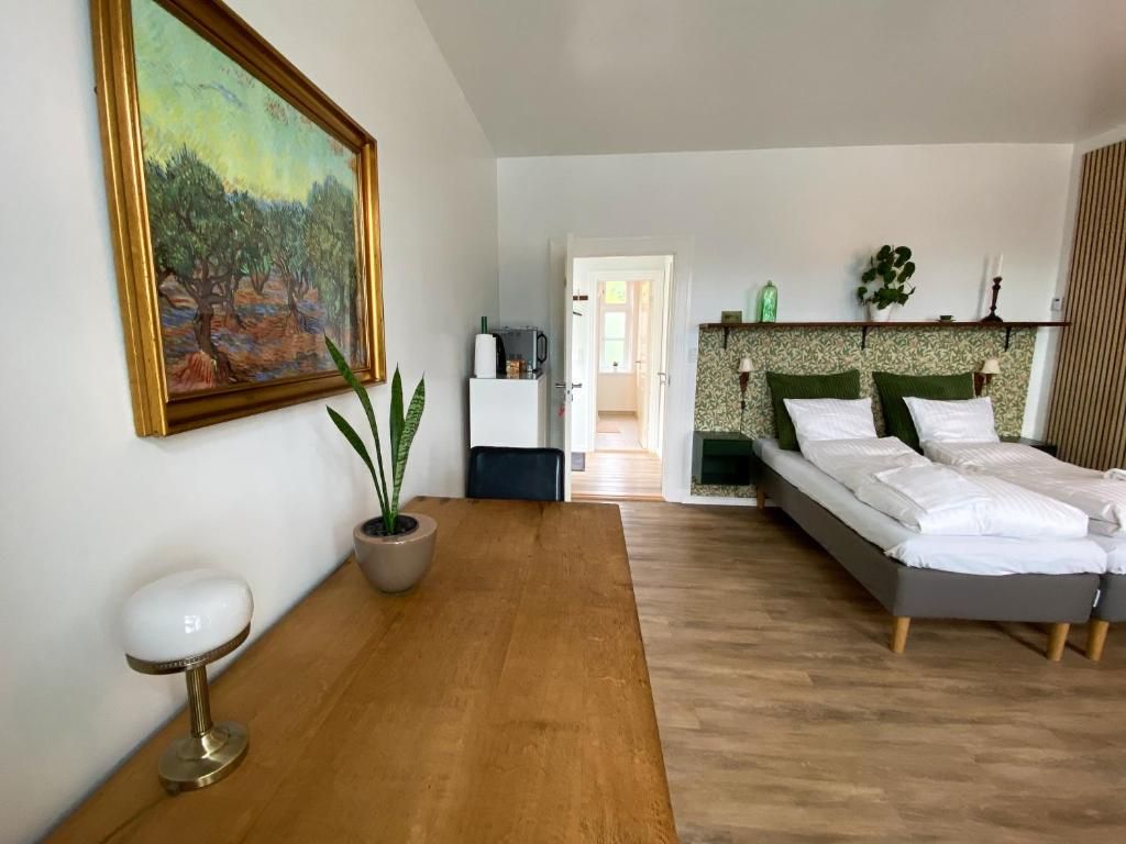 A bedroom with a bed, bedside table, lamp, and a painting on the wall.