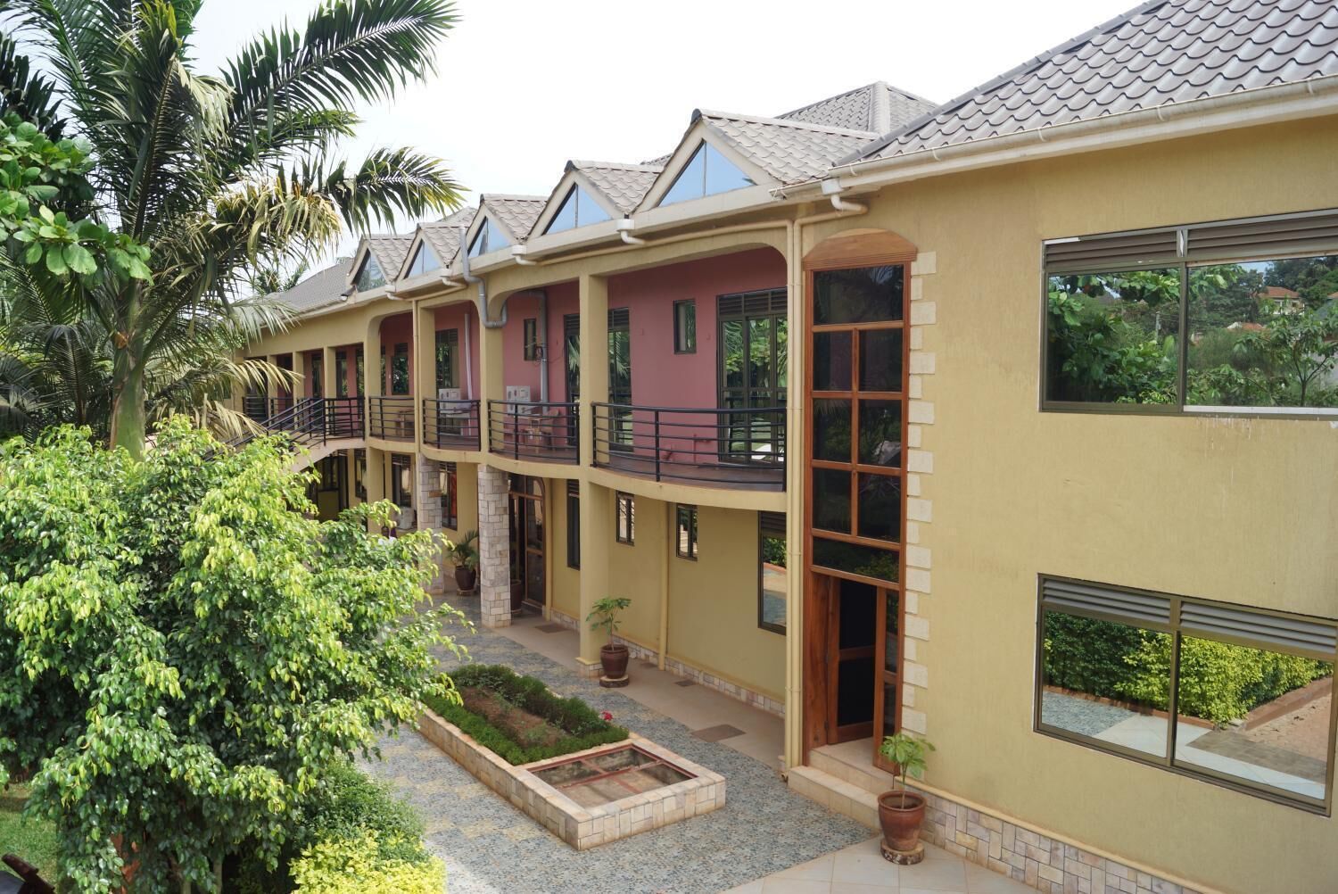 A multi-story building with balconies, a courtyard with plants, and a tiled roof.